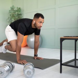 A man doing a 10-minute home workout with mountain climbers on a mat in a living room.