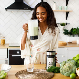 How to Boost Your Immune System Naturally – woman preparing a healthy green smoothie with fresh vegetables in a modern kitchen