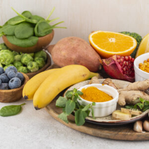 An assortment of foods that boost your immune system naturally, including citrus fruits, spinach, blueberries, ginger, garlic, turmeric, yogurt, and fresh vegetables, on a wooden table.