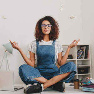 Woman practicing mindfulness meditation at home workspace to improve mental wellness and reduce stress