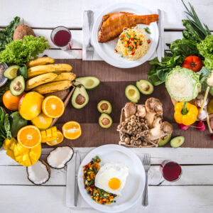 Cheap healthy foods, including fruits, vegetables, eggs, fish, and whole foods, are arranged on a table for balanced budget-friendly meals