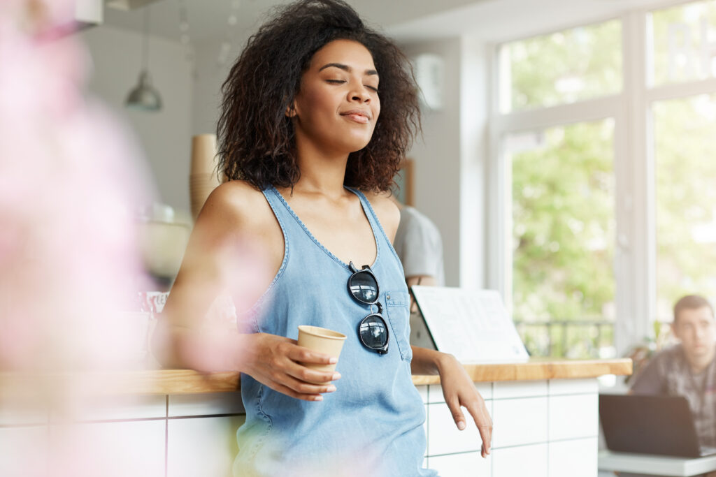 A woman practicing mindful breathing while holding coffee, representing mental wellness tips daily for stress relief