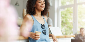 A woman practicing mindful breathing while holding coffee, representing mental wellness tips daily for stress relief