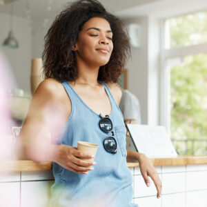 A woman practicing mindful breathing while holding coffee, representing mental wellness tips daily for stress relief